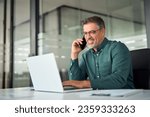 Small photo of Busy smiling older middle aged business man professional expert or entrepreneur making phone call speaking with client communicating on cellphone using laptop computer sitting at desk in office.