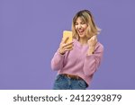 Small photo of Excited crazy gen z blonde young woman winner with smartphone, happy shopper customer student girl screaming yes using mobile cell phone celebrating online prize win on purple background.