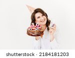 Small photo of a lilt woman with a glass of champagne and a birthday cake with candles on a white background. traditional sweet treat and wish-making for a birthday.