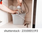 Small photo of The plumber disassembles the siphon under the sink to clear the blockage. A procedure to maintain the cleanliness and proper functioning of plumbing.
