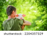 Small photo of Happy young pig on mens hands, on a garden. Friendship humans and animals. Concept of love of nature, respect for the world and love for animals. Ecologic, biologic, vegan, vegetarian