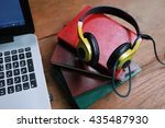 headphone and laptop on wood table , Enjoys digital music listening,Layout of comfortable working space on wooden, internet laptop headphone phone notepad pen eyeglasses laying on it

