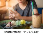 Afternoon scene of young woman using smartphone for social networking in ice cream cafe on weekend. Trendy lifestyle concept with technology.