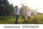 Small photo of children run through the meadow in park with toys in their hands. happy family kid dream concept. a group of little kids have fun together and play with flying kites toy lifestyle airplane