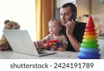 Small photo of father working from home remotely with baby son in his arms. pandemic remote work business concept. father tries to work at home in kitchen, baby children interfere sitting on their fun hands