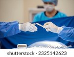 Small photo of Team of surgery doctor in Operating Room hold hands scalpel surgical blade give to Surgeons During Operation. surgeons assistance in green gown coat give scalpel surgical blade to doctor