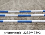 Small photo of Show jumping poles obstacles, barriers, waiting for riders on show jumping training. Horse obstacle course outdoors summertime. Poles in the sand at equestrian center outdoors
