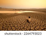 Small photo of Young man sit on dry cracked earth near drying river or lake metaphor Water crisis, Drought and climate change.