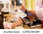 Person paying at cafe with smart watch wirelessly on POS terminal