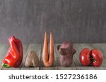 Imperfect red pepper, carrot,  sweet potato, red tomato arranged in a row on a wooden background. Food concept, imperfect produce concept.Image with copy space.