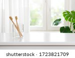 Small photo of Two wooden toothbrushes in glass on blurred window background