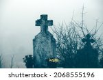 Small photo of Misty view of dark stone crosses and tombstones in a deserted graveyard. Halloween concept