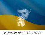 Sad woman with Ukraine flag at background praying. Concept of standing with Ukrainian nation in war with Russia.