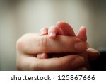 Newborn baby holding his mothers finger, selective focus
