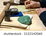Geologist works with maps. On his desk are: map case, geological hammer, compass, magnifying glass, drill core, rock samples, topographic and geological maps