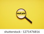 Small photo of small print enlarged with magnifying glass magnifier loupe, minimal concept on yellow background with copy space