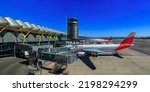 Small photo of Madrid, Spain - June 28, 2021: Modern architecture of a terminal in Madrid International Airport, Aeropuerto Madrid Barajas, MAD and an Iberia plane