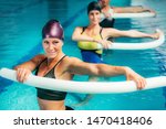 Aqua Aerobic Training with Water Fitness Equipment. Women Training with Swimming Noodles.