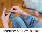 Knitting. Senior woman knitting at home. Cognitive enhancement ability.