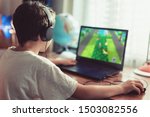 Small photo of Little dependent gamer boy playing on laptop at home