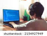 Small photo of Young geek boy with headphones coding on laptop at home