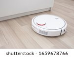 White robot vaccum cleaner on the floor in the living room