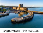 Medieval Norman Castle and harbor in Carrickfergus near Belfast, Northern Ireland, UK. Aerial view  in sunset light. Old power plant in the background
