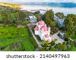 Small photo of Pink domes with golden crosses of the monastery on the shores of the Sea of Galilee. Tropical park around Greek Orthodox monastery of the Twelve Apostles. Capernaum. Israel