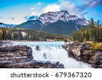 The waters of a melting mountain glacier feed the seething waterfall of Athabasca. The red deer on the waterfall. Travel to Jasper Park, Canada. The concept of extreme and ecological tourism