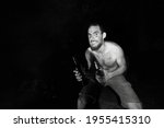 Small photo of Wild man grabbing bottle in the dark by a campfire, uncivilized look