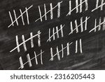 Small photo of Drawing counting tally chart with chalk, marks in groups of five, counting days
