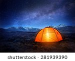 A tent glows under a night sky full of stars. 