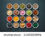 Various colorful superfoods as acai powder, turmeric, matcha green tea, spirulina, quinoa, pumpkin seeds, blueberry, dried goji berries, cape gooseberries, raw cocoa, hemp seeds  on dark background