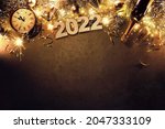 New Years Eve holiday background with fir branches, clock, christmas balls, champagne bottle, gift box and lights on dark board