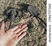 Small photo of an antique gold ring in the hand of a searcher, found on an old tract with the help of a metal detector, the foreground and background are blurred with a bokeh effect