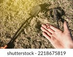 Small photo of an antique gold ring in the hand of a searcher, found on an old tract with the help of a metal detector, the foreground and background are blurred with a bokeh effect