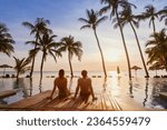 couple on the beach at sunset, honeymoon travel, man and woman sitting near swimming pool in hotel resort