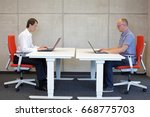 two men coworking in correct sitting posture on chairs in office