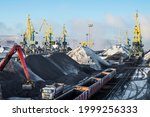 Small photo of Heaps of coal on the territory of the seaport. Coal is unloaded from wagons by all kinds of cranes, then loaded into the holds of sea ships. The work is carried out around the clock