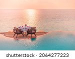Seascape view under sunset light with dining table with infinity pool around. Romantic tropical getaway for two, couple concept. Chairs, food and romance. Luxury destination dining, honeymoon template