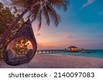 Tropical sunset beach background, summer island landscape with beach swing or hammock and sand romantic sea beach. Beautiful beach scene vacation or summer holiday concept. Honeymoon, romance resort
