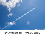 Airplane contrail against skyblue sky with white cloud .