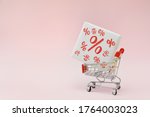 Image of empty shopping trolley or cart with box of discount percent sale black Friday products on pink background. Concept of sell or buy with place for your text