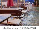 Selective focus and night view, red and white caution tape wrapped around outdoor tables and seats area of cafe which covered by snow and closed by lockdown during epidemic COVID-19 in winter season. 