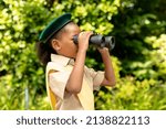 Small photo of African american scout girl in uniform looking through binoculars in forest. unaltered, girl scout, childhood, exploration, discovery, adventure and scouting.