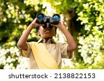 Small photo of African american scout girl in uniform looking through binoculars while exploring in forest. unaltered, girl scout, childhood, exploration, discovery, adventure and scouting.
