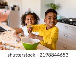 Small photo of Happy african american siblings baking in kitchen. baking and cooking, childhood and leisure time at home.