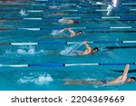 Small photo of High angle side view of multi-ethnic group of male swimmers at swimming pool, racing each other in lanes, swimming crawl