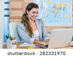 Small photo of Pretty travel agent working on laptop in the office