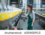 Female factory worker inspecting production line at drinks production factory
